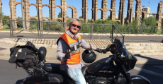 Monti Galmés posando con su motocicleta frente al puente romano de Mérida. Foto: Facebook.